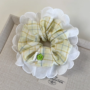 Detail of yellow checkered scrunchie with lace trim, green button, and Hand Made label
