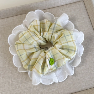 Detail of yellow plaid scrunchie with white lace trim and handmade label ornament