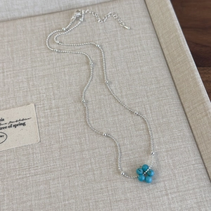 Gros plan d'un collier fleur en argent avec pierres bleues sur un plateau