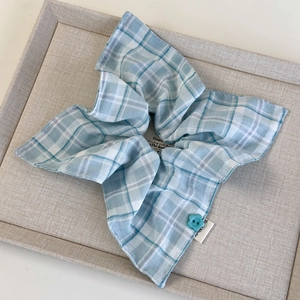Detail of blue and white plaid hair scrunchie with a floral button and handmade woven label