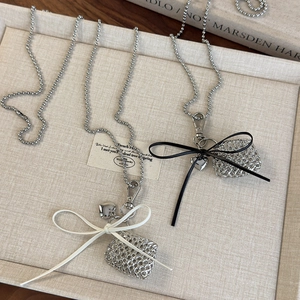 Close-up of silver hollow rectangular pendants with white and black ribbon bows on ball chains