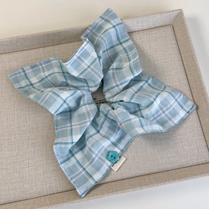 Detailed shot of blue plaid scrunchie with floral button and handmade label tag