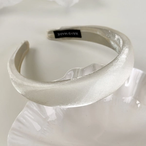Detailed macro view of white satin headband texture and handmade interior label