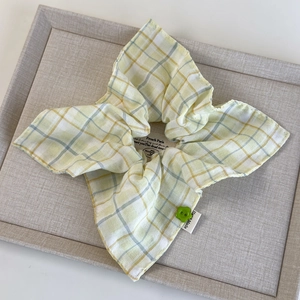 Close-up of yellow plaid fabric scrunchie with lace edge and green floral button detail