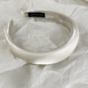 Detail view of thickened pearl satin sponge headband in elegant champagne silk fabric