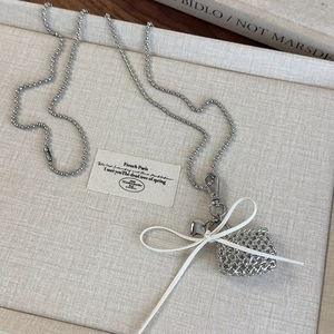 Silver bead chain necklace with woven wire bag pendant and white bow detail closeup