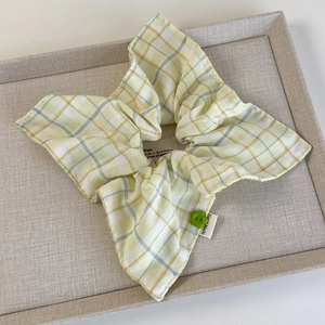 Detail of yellow plaid scrunchie with a green flower button and lace edge finish