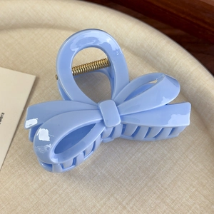 Détail de la pince à cheveux en acrylique bleu clair en forme de nœud avec ressort doré