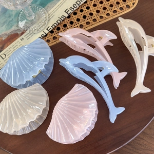 Detailed view of dolphin and shell hair claws in pastel colors with pearlescent finish