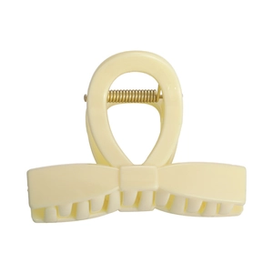 Pince à cheveux beige crème en forme de nœud avec ressort doré sur fond blanc