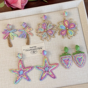 Detailansicht geflochtener Strohohrringe mit Seestern, Palme und Blumendesigns