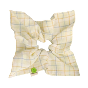 Detail view of plaid scrunchie with a green flower button and Hand Made label