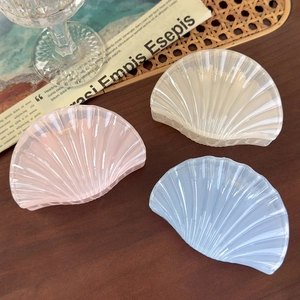 Detailed view of three shell-shaped hair claws in pastel pink, cream, and soft blue colors