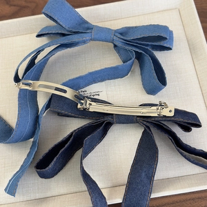 Detailed close-up of denim bow hair clips with contrast stitching and metal spring clips