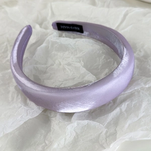 Detail of lavender satin headband showing padded texture and handmade inner label