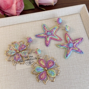 Detailansicht bunter gewebter Bast-Ohrringe in Seestern- und Blumenform im Boho-Stil