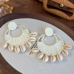 Bohemian large straw woven hoop earrings with white cowrie shells for summer beach vacations