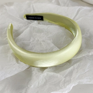 Detail of light green satin headband with handmade label and glossy padded silk texture