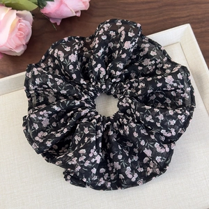 Détail du chouchou floral avec fleurs roses sur tissu noir pour coiffures chic