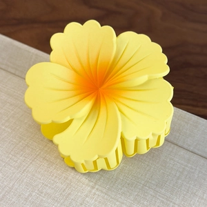 Macro detail of matte gradient yellow flower hair claw clip with orange center