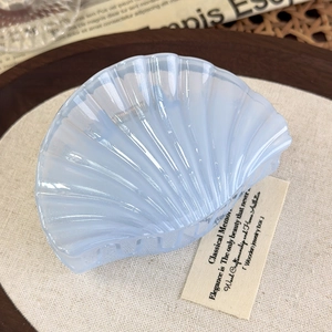 Close-up of a light blue pearlescent shell hair claw clip on a rustic linen background