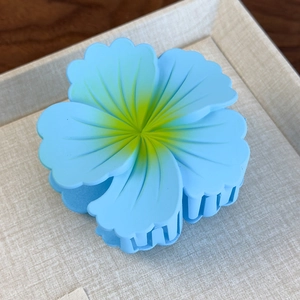 Close-up of sky blue matte flower hair claw with yellow and green gradient detail