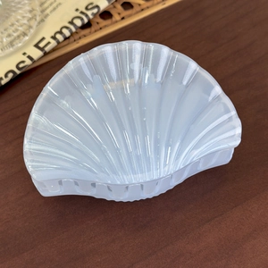 Detailed macro view of a translucent blue shell-shaped hair claw on a rustic wooden table