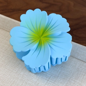 Detailed macro view of light blue gradient flower hair claw with matte finish resin texture
