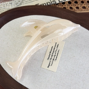 Detail of cream dolphin hair claw clip with golden metal spring on a vintage background