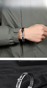 Détail macro du bracelet en cuir noir tressé avec surpiqûres blanches et croix en métal argent