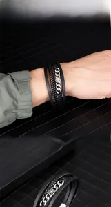 Detailed close-up of multilayer braided leather bracelet with silver metal star and cross details