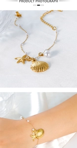 Bracelet doré avec coquillages, étoiles de mer et perles sur soie et porté au poignet
