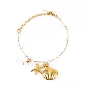 Bracelet doré avec breloques coquillage et étoile de mer et perles blanches sur blanc