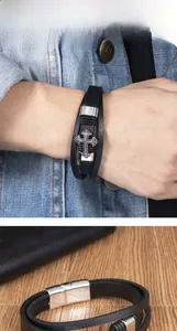 Detail of men's multilayer black leather bracelet with silver cross and magnetic clasp