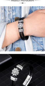 Macro shot of double-layered black woven leather bracelet with vintage silver nautical helm charm