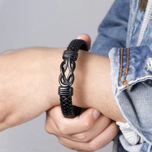 Men's black braided leather bracelet with a metal knot detail on a denim background
