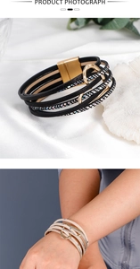 Detail of multi-layer leather bracelet with magnetic clasp and gold heart charm