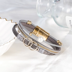 Mehrlagiges Boho-Lederarmband mit Kunstperlen und Magnetverschluss auf weißem Stoff