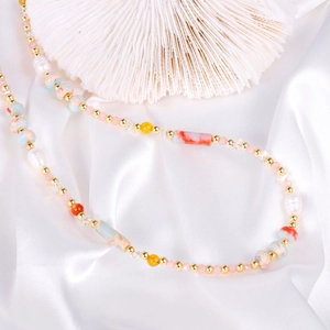 Bunte Naturstein-Perlenkette mit weißen Perlen und Goldakzenten auf Seidenstoff