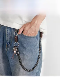 Detail of vintage hip hop wallet chain with skull hook and horn pendant on blue jeans