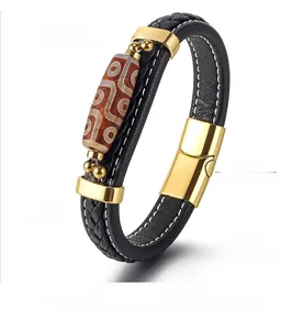 Detail view of woven leather bracelet with patterned bead and gold metal clasp