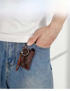 Deep brown leather lighter case keychain hanging from a blue denim jeans pocket