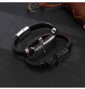 Dettaglio bracciale in pelle intrecciata con elemento a croce e chiusura magnetica