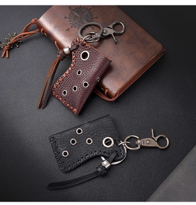 Detail of axe-shaped leather lighter cases with vintage metal hooks on dark textured surface