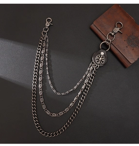 Detail of triple-layer punk pants chain with skull metal charms and dark leather