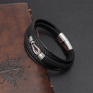Men's multilayer black leather bracelet with infinity knot symbol on vintage notebook