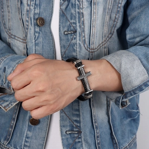 Bracciale da uomo in pelle nera intrecciata con croce d'argento vintage su giacca jeans