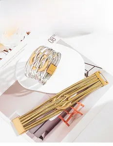 Détail de bracelets métalliques larges multirangs avec cercle croisé et fermoir aimanté