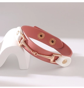 Nahaufnahme von rosa Lederarmband mit goldener Trensenschnalle und Druckknopfverschluss