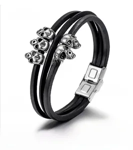 Detail of multi-layer leather bracelet featuring five silver skulls and magnetic clasp